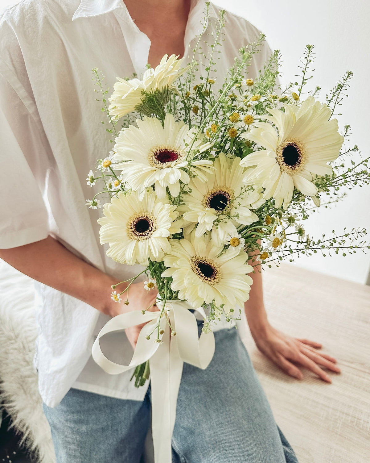Person holding a bouquet of white flowers with a blurred background